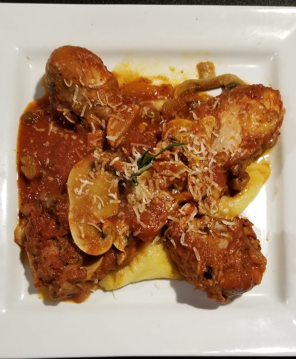Braised chicken in tomato sauce with mushrooms and rosemary, spooned over soft polenta